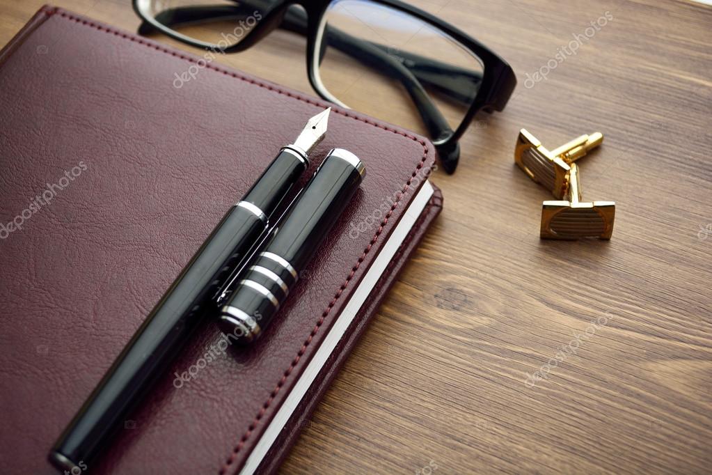 Business accessories on desktop: notebook, diary, fountain pen, cufflinks,  glasses. Stock Photo by ©miztanya 117101176